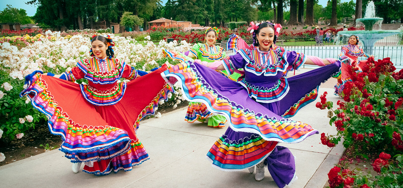 Dancers in tradition Mexican dresses dancing among thousands of rose buds in the Municipal Rose Garden.