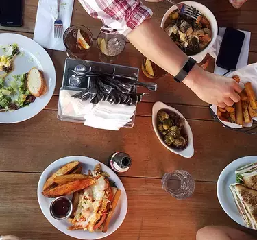 Top view of a table loaded with delicious lunch dishes and friends at Park Station Hashery.