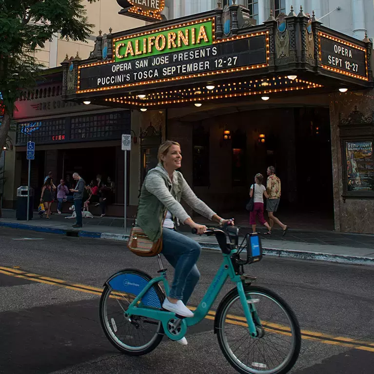 Woman riding Ford GoBike in front of California Theatre