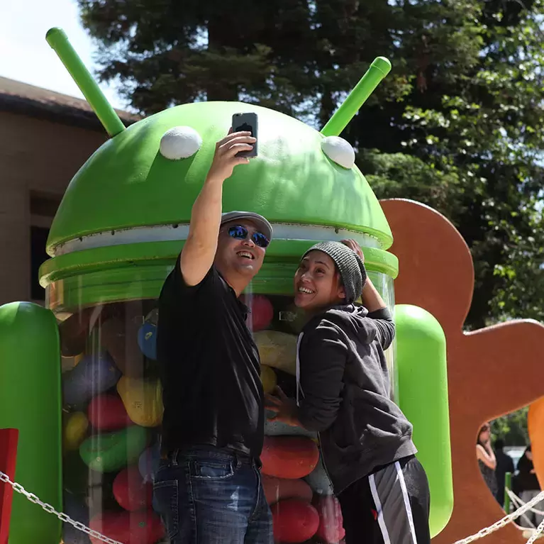 Friends take a selfie in front of the Android statue at the Google Statue Garden