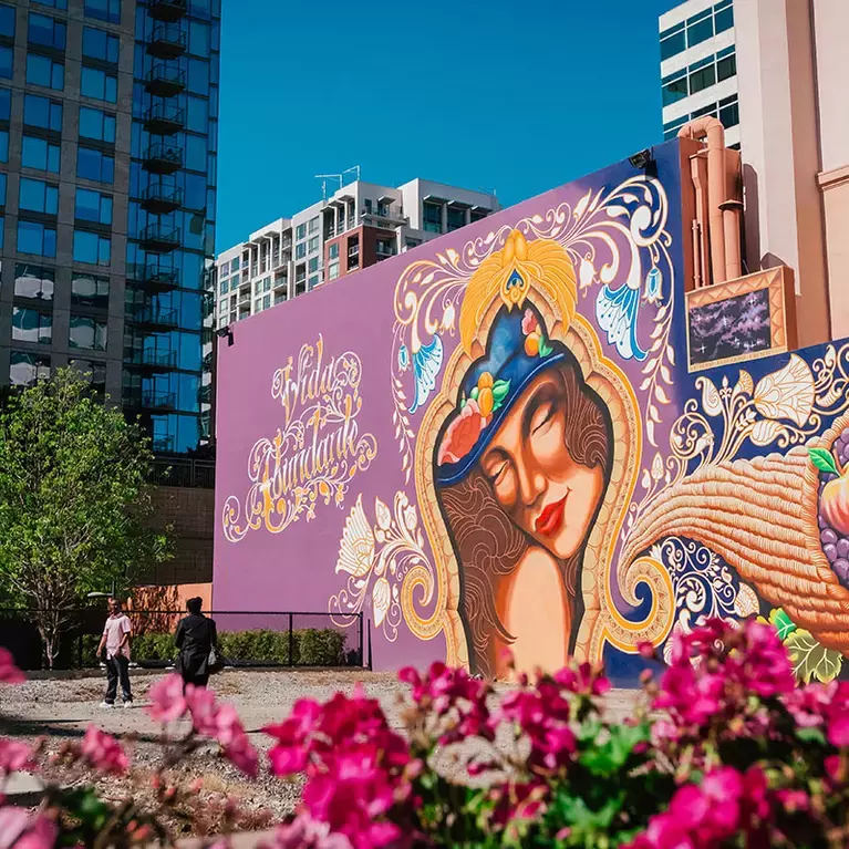 The colorful Vida Abundant mural, a woman with cornucopia, painted on the side of Hotel De Anza