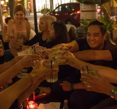 A group enjoying happy hour and dinner outdoors at El Jardin Tequila Bar