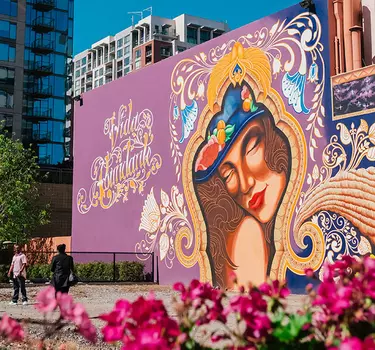 People taking pictures posing in front of the giant mural along side of the historic Hotel DeAnza