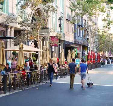 Santana Row strip with people shopping and dining curb side.