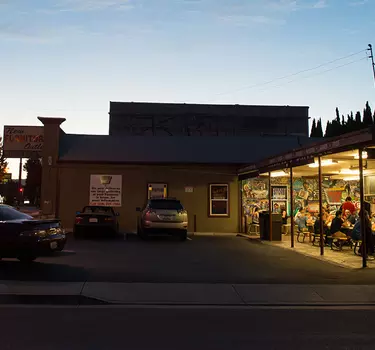 The Falafel Drive-In walk-up-to-order stand and bright neon sign glowing at night.