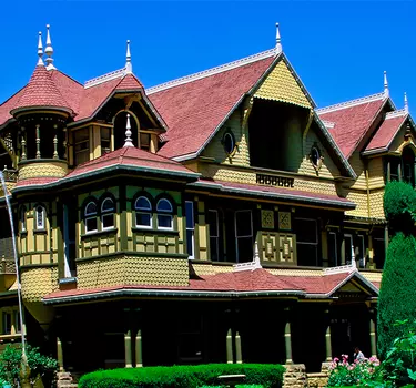 Exterior of the Winchester Mystery House featuring the beautiful gardens and fountain in front.