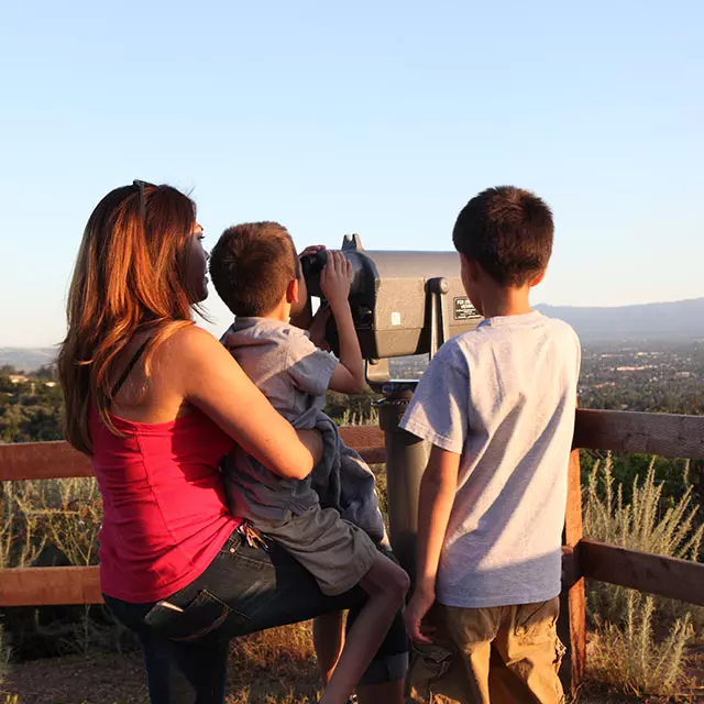 A family viewing San Jose and Silicon Valley from a telescope on a trailhead lookout at Alum Rock Park