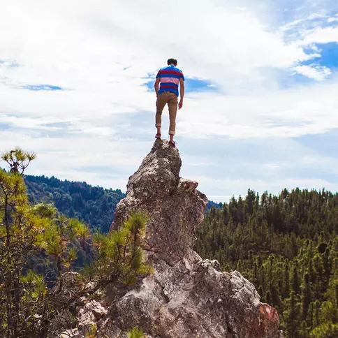 A hiker standing on top of a mountain peak overlooking the gorgeous redwood draped Big Basin Redwoods State Park