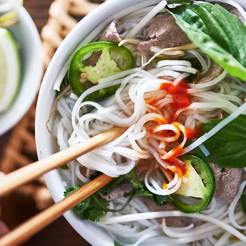 Close-up of bowl of Asian food with chopsticks