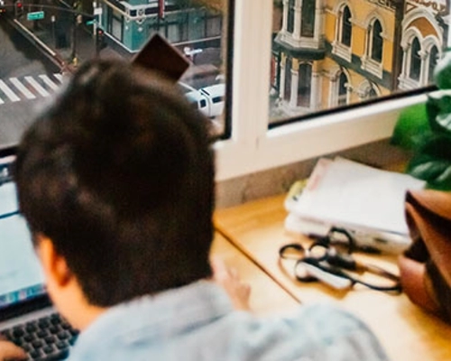 A man working at a desk with views of downtown and City Hall