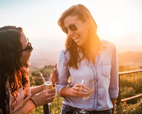 Women enjoying cocktails outdoors at the GranView Restaurant with the sun setting over the Silicon Valley in the background