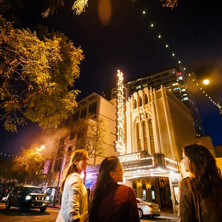 Women standing in front of San Jose's California Theatre at night 