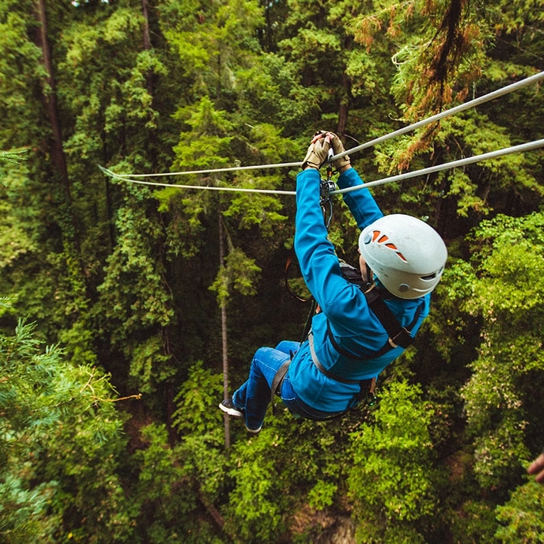 A woman ziplines through the redwoods at Mount Herman Adventures in Felton