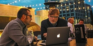 Two gentlemen work at a laptop on the outside patio of Scott's Seafood in San Jose